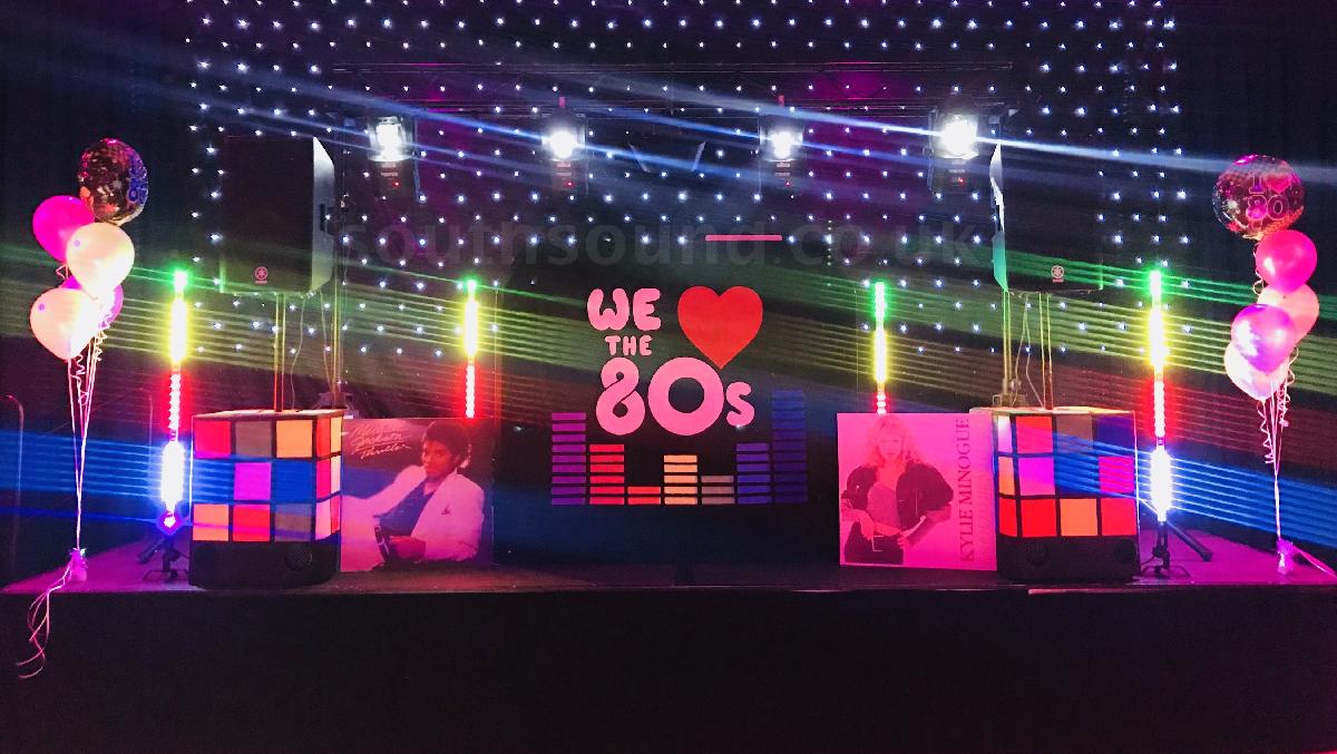 Colorful stage adorned with neon lights and balloons at Southsound Disco, a retro 80s music themed retro disco.